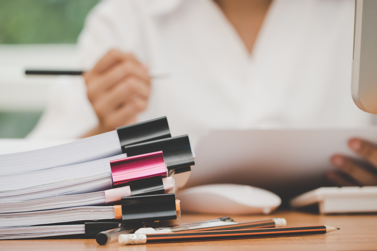 corporate investigator at a desk with stacks of papers clipped together